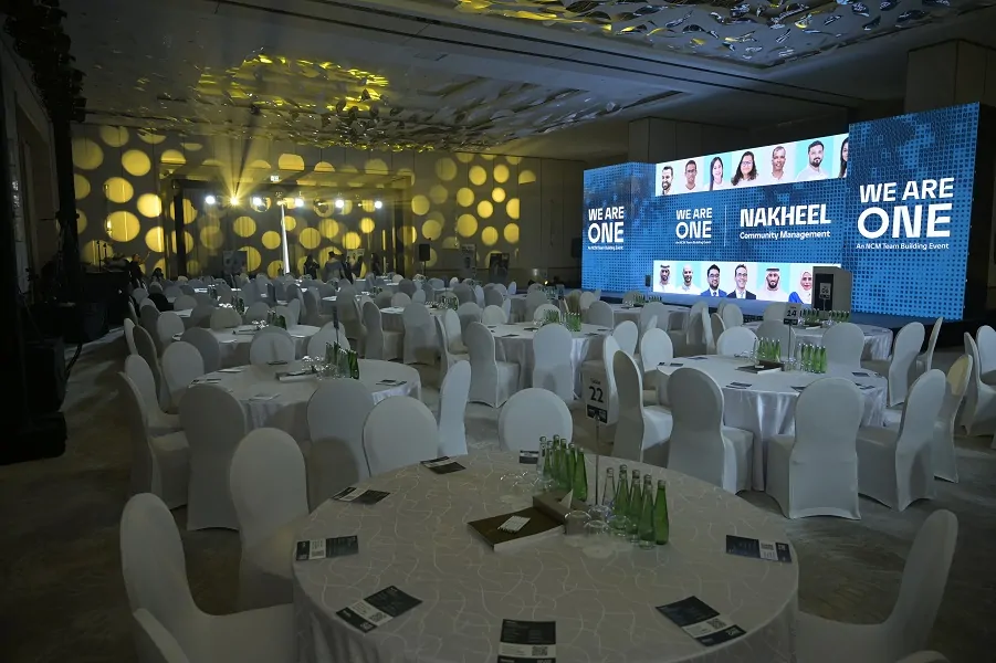 Ballroom with round tables and We Are One LED screens at the Nakheel Properties team building event 2023 in Dubai, by Topaz Events