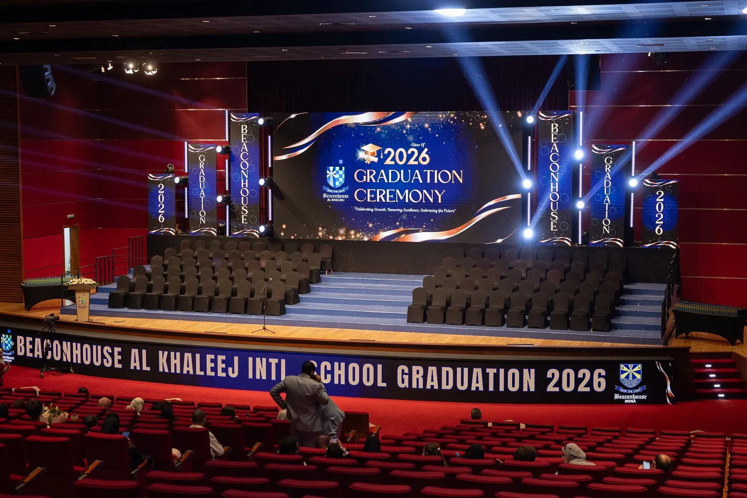 Tiered graduation stage with LED screen, blue lighting and branded pillars before the Beaconhouse ceremony in Dubai