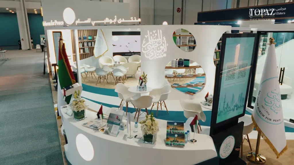 Open curved Abu Dhabi Forum for Peace stand with Arabic calligraphy, library and seating at the Abu Dhabi International Book Fair