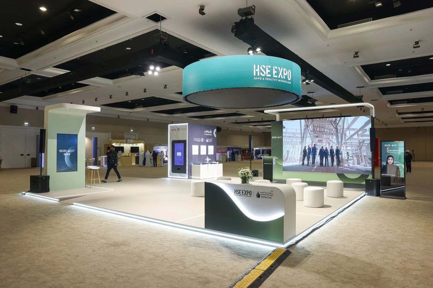 Wide view of the SNOC exhibition stand at HSE Expo 2026 with curved reception desk, circular overhead screen and LED wall at Al Jawaher, Sharjah