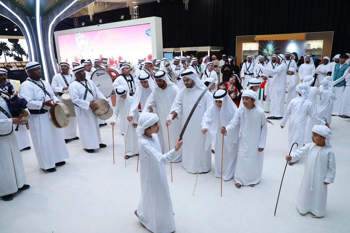 Emirati folk troupe with drums and canes performing at the LIWA Ajman Dates & Honey Festival 2025, Ajman