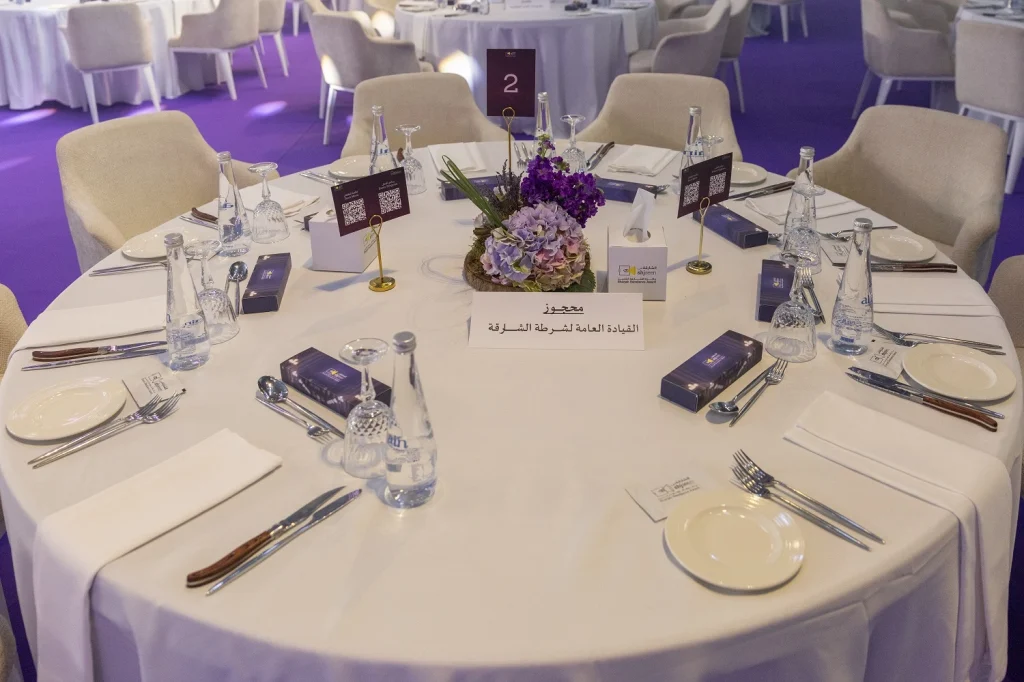 Round dinner table with a purple floral centrepiece and place settings at Shjseen 2026