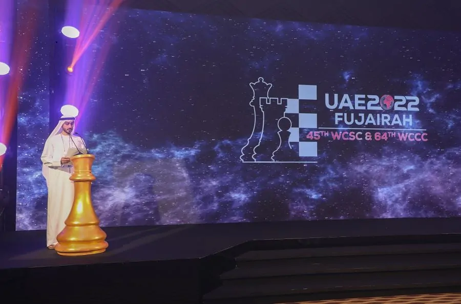 Speaker on stage beside a giant golden chess piece and UAE 2022 Fujairah LED screen