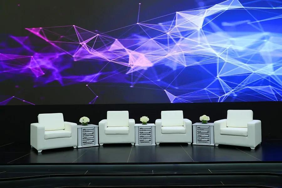 White lounge seating for panel speakers in front of an LED screen at the Fujairah philosophy conference