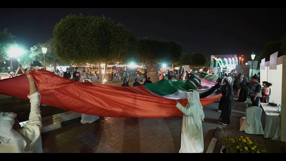 Visitors carrying a giant UAE flag through Sharjah National Park during the 53rd Eid Al Etihad festival