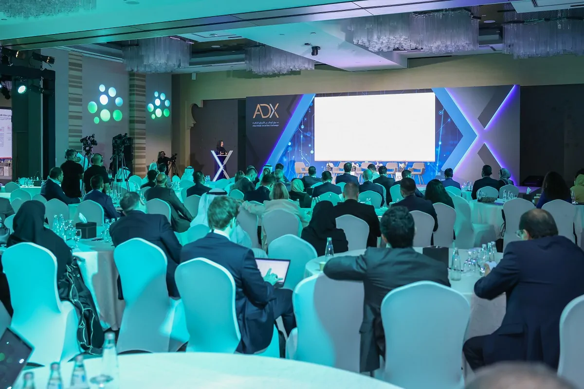 Investors and delegates attending a session in front of the ADX branded LED stage at the Abu Dhabi Securities Exchange Conference 2024 by Topaz Events