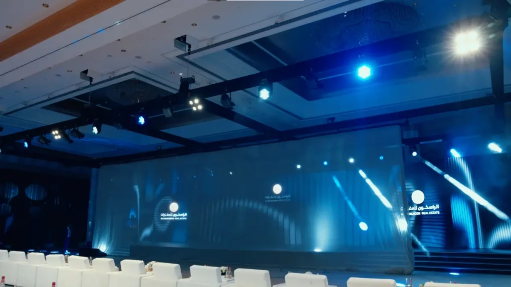 Panoramic LED stage backdrop and blue stage lighting before the Al Rasikhoon Real Estate launch 2025, Ajman