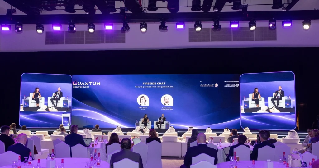Panel discussion on stage with speakers seated in front of the wide LED backdrop