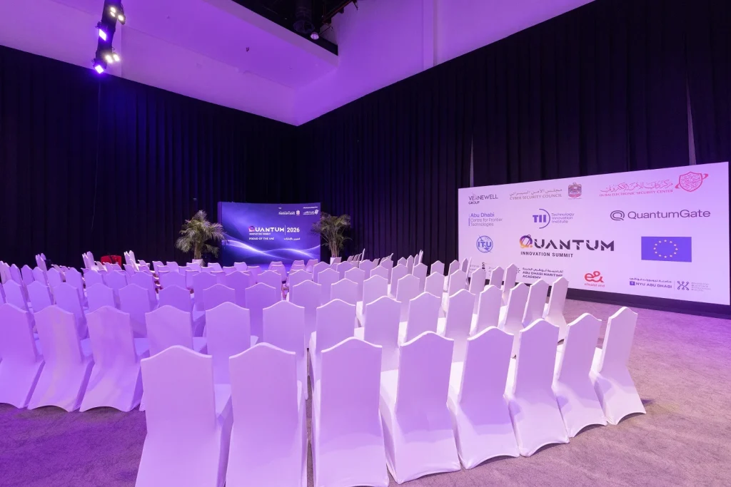 Breakout room with rows of white covered chairs and a Quantum branded backdrop