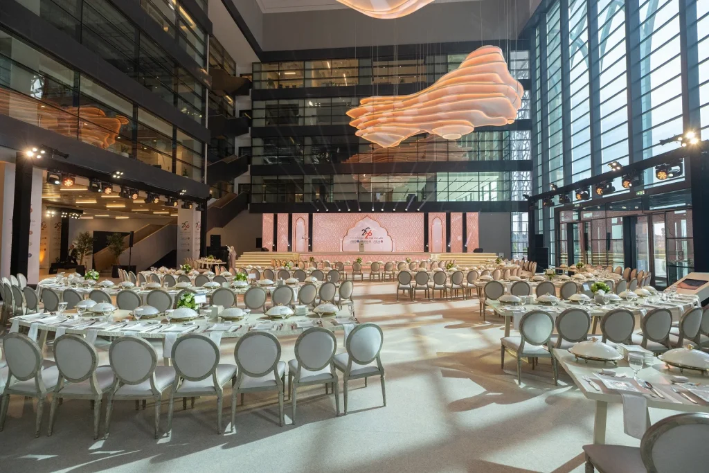 Banquet tables set beneath the large pink suspended ceiling sculpture in the forum venue