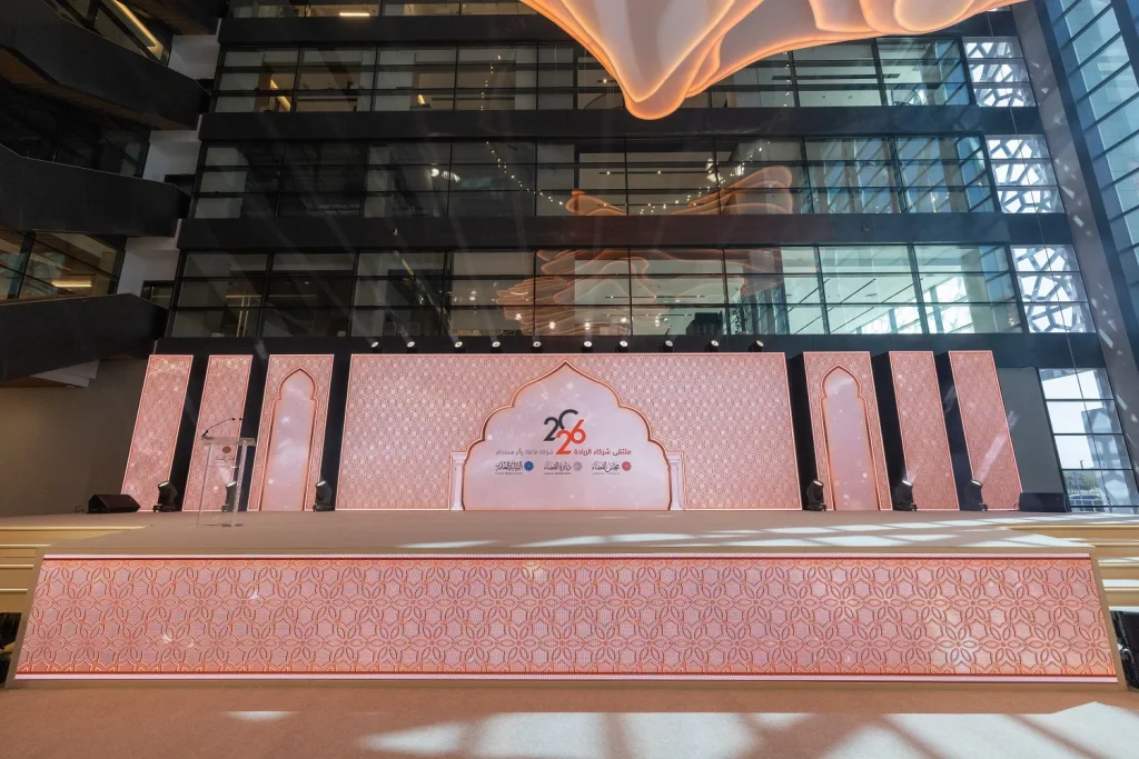 Pink arabesque stage set with 2026 forum branding in the glass atrium at the Sharjah Judicial Department Forum 2026