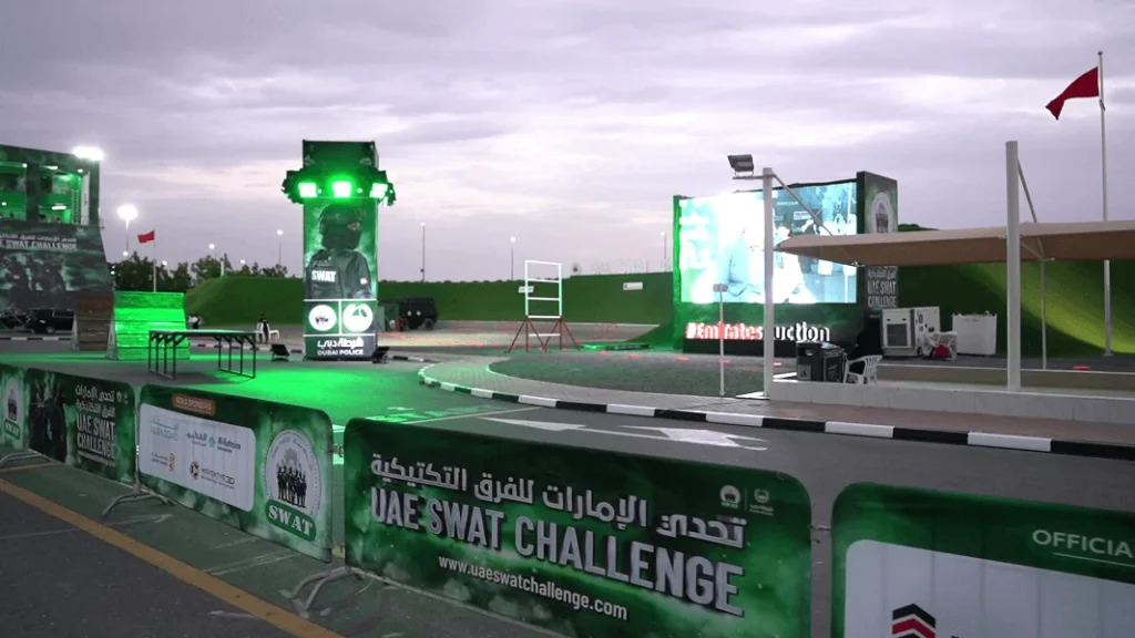 Branded challenge course with green-lit tower and LED screens at the Dubai Police SWAT Challenge 2024, organized by Topaz Events
