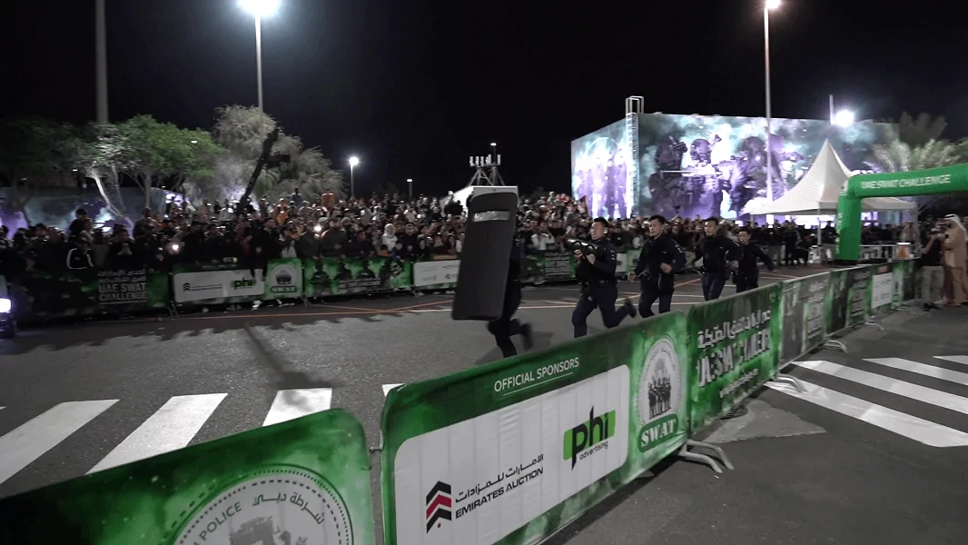 Spectators watching a tactical team run the course in front of a giant LED screen, Dubai Police SWAT Challenge 2024