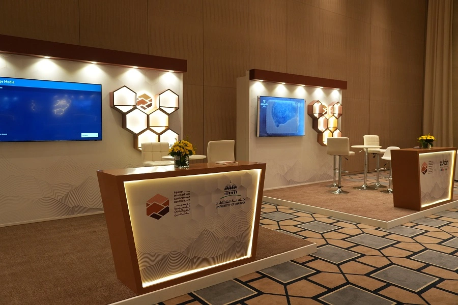 Partner exhibition booths with lit counters and hexagon displays at the Fujairah International Conference on Bee Research 2023
