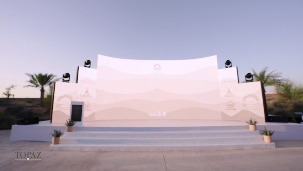 Curved stage set with desert-inspired visuals and lighting rig at dusk, SCCI Annual Ceremony 2024