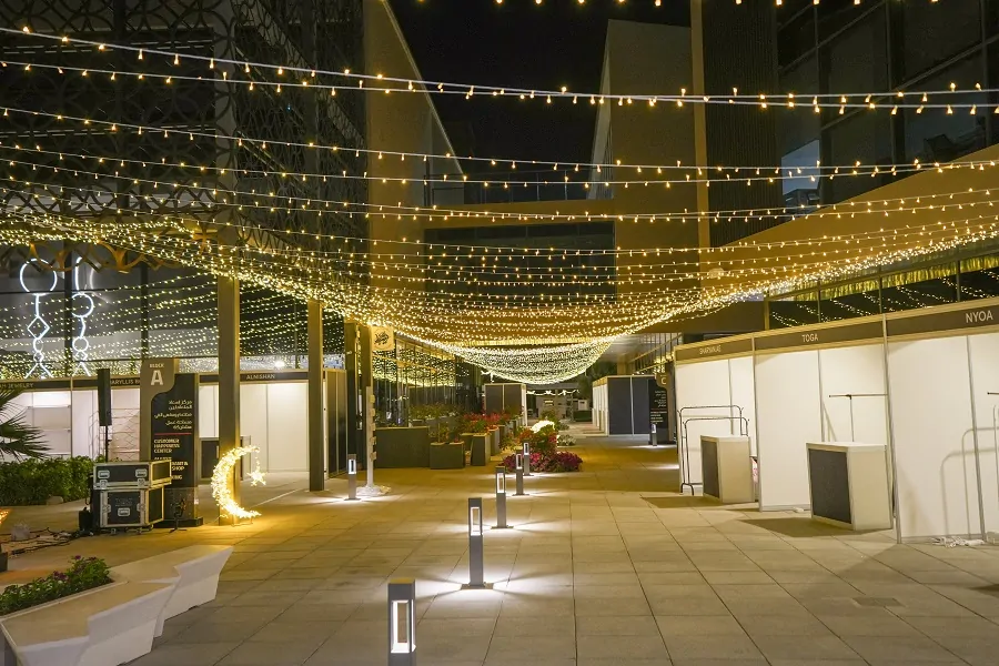 Walkway under a canopy of fairy lights with souq stalls at the Shams Ramadan Festival 2024, Sharjah
