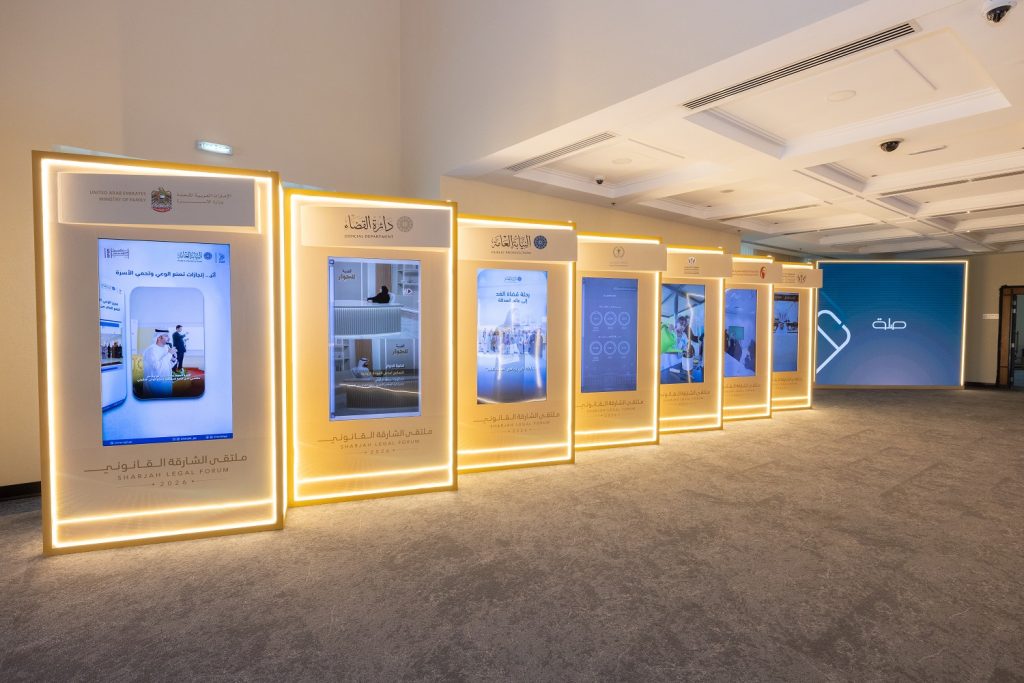 Row of lit digital display screens along the exhibition walkway at the Sharjah Legal Forum 2026
