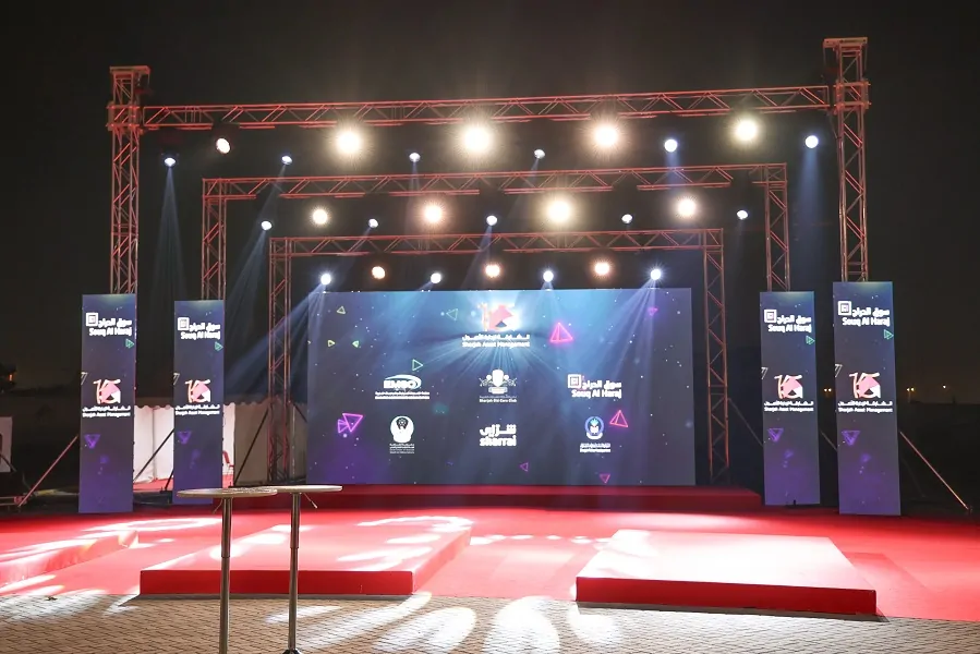 Red-carpet stage with LED screen, truss lighting and branded pylons at Sharjah Asset Management’s 15th Anniversary, Souq Al Haraj 2024