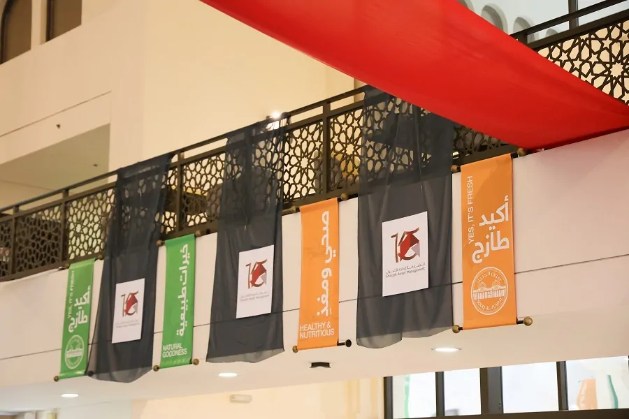 Hanging 15th anniversary banners and red drapes inside Souq Al Jubail, Sharjah Asset Management 2024