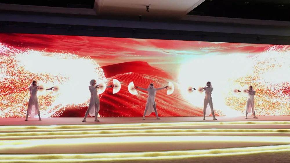 Dancers performing in front of an interactive sensor screen that reacts with red and white motion visuals