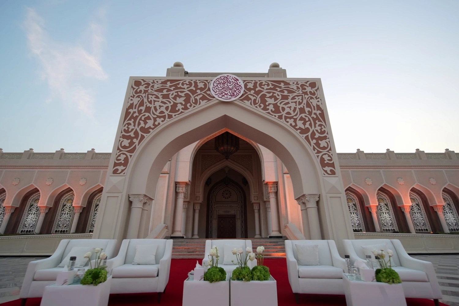 Premium VIP lounge setup by Topaz Events for the Sheikh Sultan Award. The reception area features high-end white furniture, custom floral centerpieces, and a red carpet installation, perfectly framed by the venue's traditional Islamic architecture.