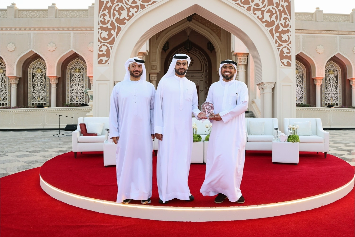 Official award presentation moment on the main stage, capturing management receiving a recognition shield against the backdrop of the event venue.