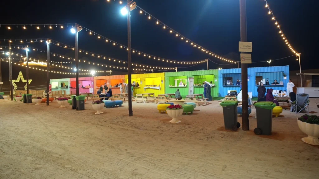 Colourful festoon-lit kiosks and seating at Aisha Oasis for Innovation 2026 at night