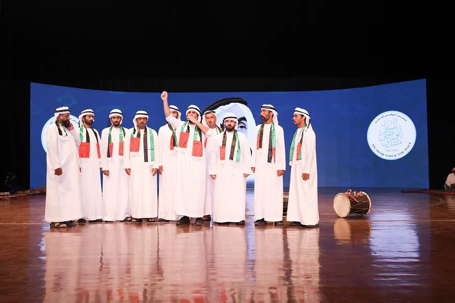 Emirati Ayyala performers on stage before the Abu Dhabi Forum for Peace LED screen at the National Day celebration